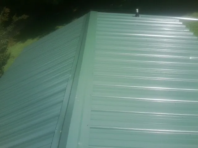 New green metal panels meeting at the ridge of a roof — Flat Roof Repair work by our crew in Waitsburg
