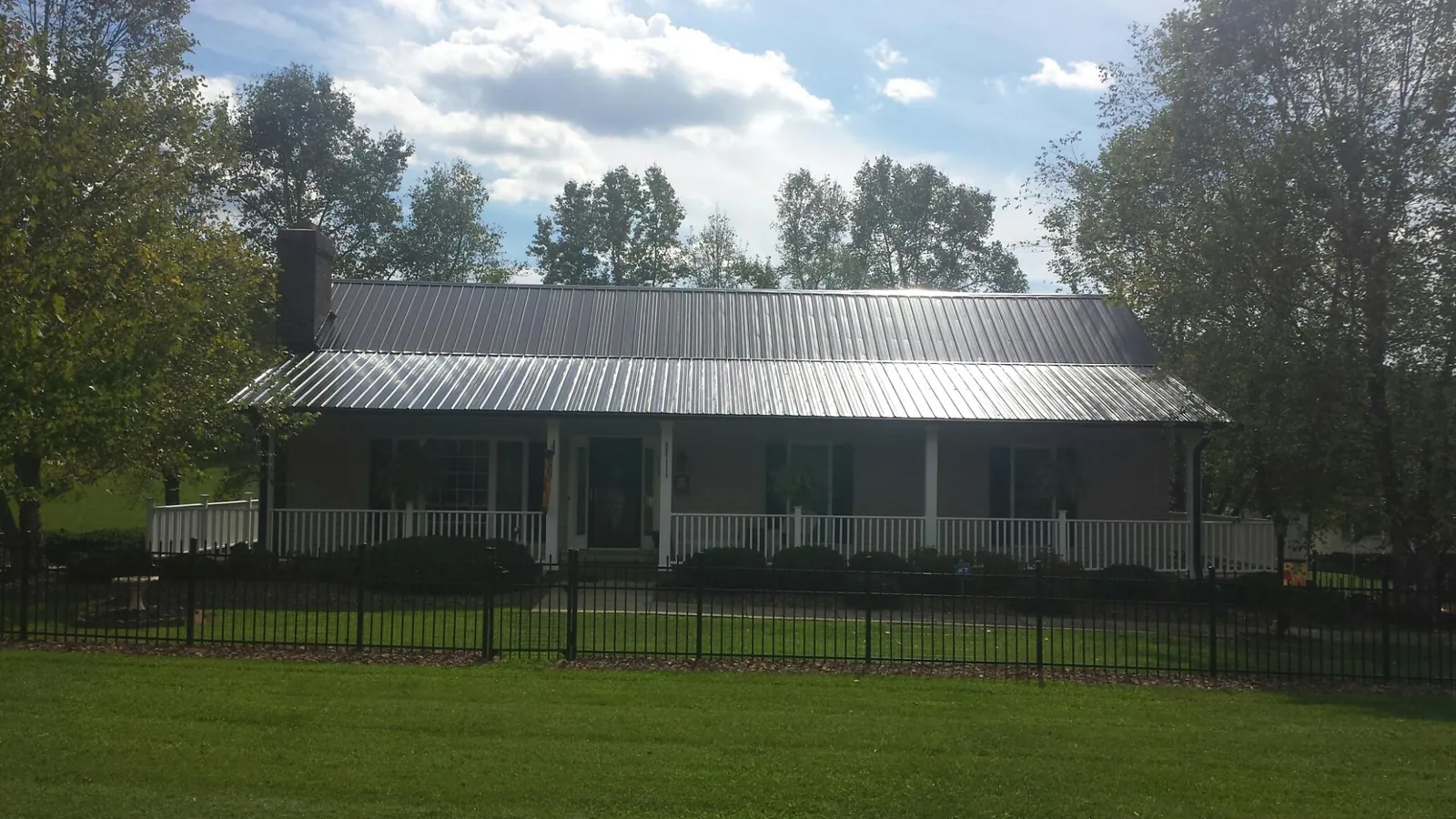 Gray metal roof on a brick ranch with a full width front porch — Gutter Guard Installation work by our crew in Waitsburg