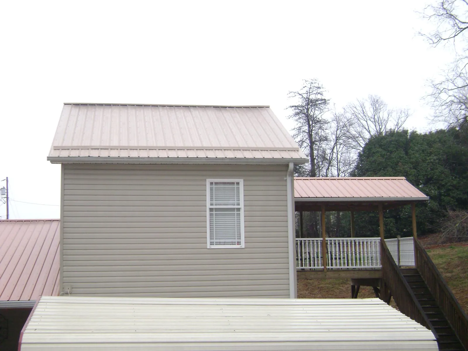 Tan metal roofs on a two story addition and attached porch, from a Roof Replacement job in Waitsburg