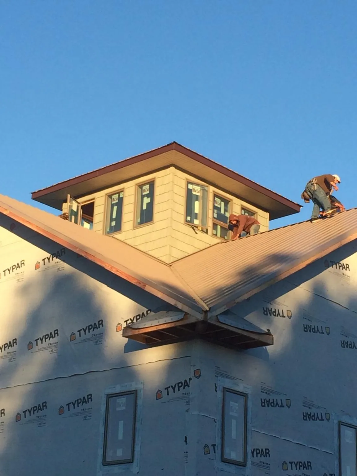 Roofers working around a rooftop cupola on a new metal roof at sunset — Roof Waterproofing in Waitsburg by Roofing Brothers